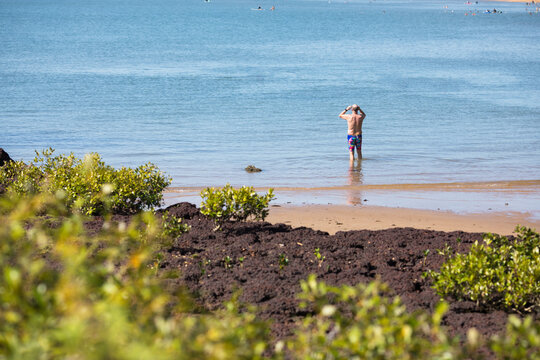 A male middle aged open water swimmer standing in the water at Suttons Beach, Redcliffe