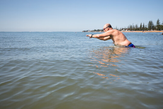 Male open water swimmer about to dive into the water