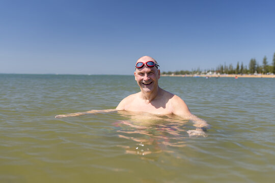 Male open water swimmer with goggle on head smiling in portrait