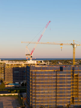 Aerial view of a tower cranes on top of a high-rise building under construction in golden light