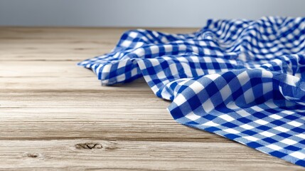 Obraz premium Close-up of blue and white checkered cloth on light wooden surface showing rustic texture, elegant folds, dining table decor, cozy home interior, kitchen styling, farmhouse concept