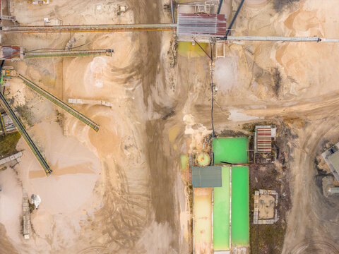 Aerial view of a sprawling industrial landscape where sand and machinery blend under a muted sky, the scene defined by a mix of earth tones, Magliano de' Marsi, Abruzzo, Italy.