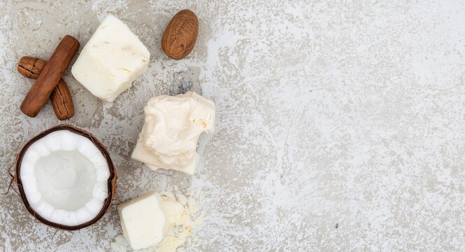 Organic body cream and scrub with natural coconut and shea butter on textured background with copy space