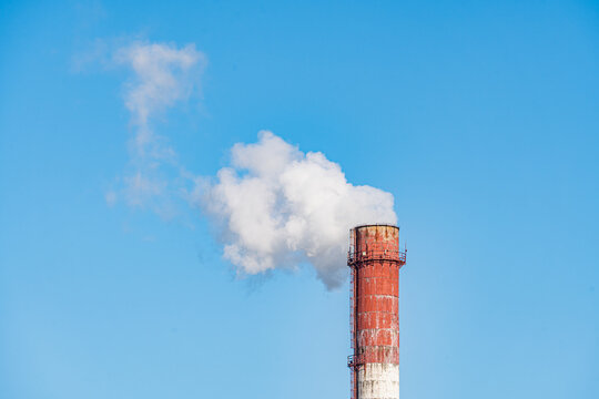 Aerial view of a towering chimney releasing plumes of white smoke against the stark blue sky, Kyiv, Kyiv city, Ukraine.