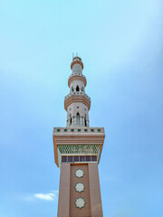 Fototapeta premium Low angle view of a tall mosque minaret under a clear blue sky. Islamic architecture, religious landmark, and traditional tower design with star ornaments.