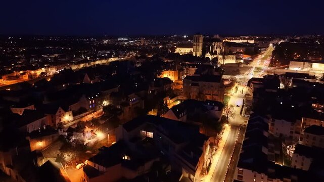 Dramatic nighttime drone fly toward the historic Le Mans Cathedral aka Cathedral of Saint Julian with glowing streets, Le Mans, France
