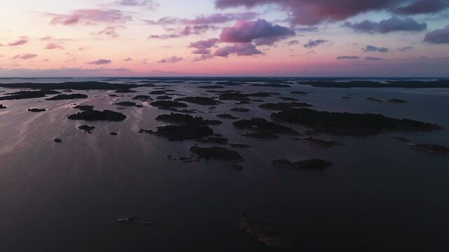 Panoramic drone shot around Finnish archipelago islands silhouette, sunset in Oro