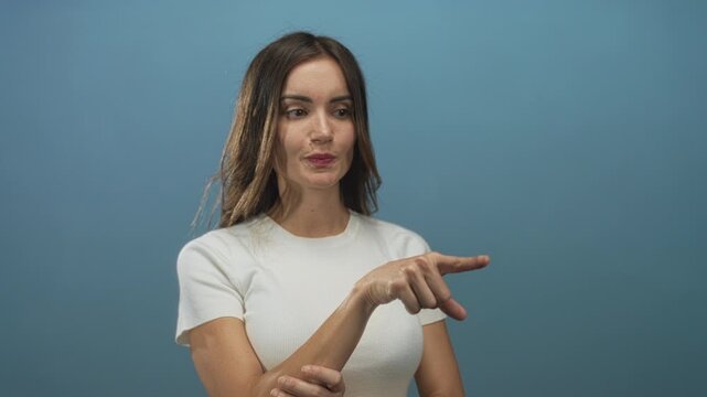 Woman clasping hands and pointing finger with pursed lips in blue studio under indirect light; confidence empowerment.