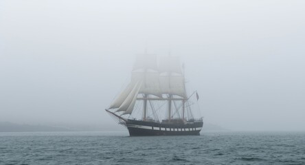 Fototapeta premium Old tall ship cruising through coastal fog