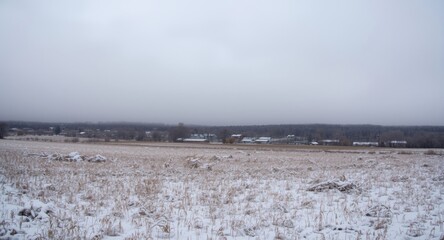 Fototapeta premium Snow covered open farm field in rural setting with thick cloud layer