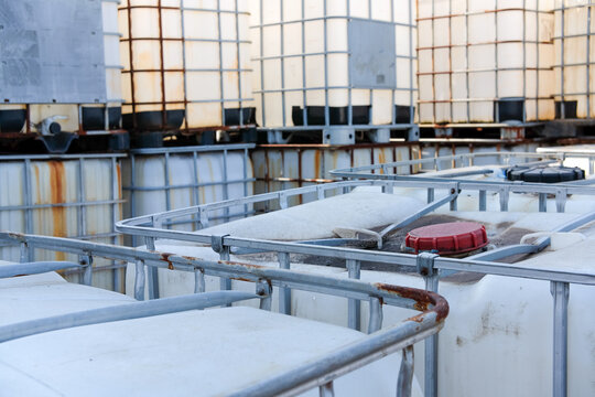 Industrial Intermediate Bulk Containers or Ibc Totes Stacked Outdoors in a Storage Yard Awaiting Reuse or Recycling for Various Liquids and Materials