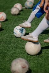 Obraz premium Children playing soccer on artificial turf with multiple soccer balls scattered