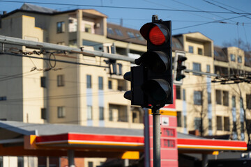 City traffic signal showing red in front of residential buildings and service station, urban mobility and street control © K