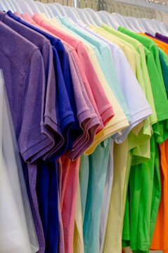 Colorful assortment of folded cotton t-shirts displayed on hangers
