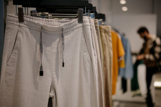 Light-colored men's trousers on a hanger in a modern clothing store