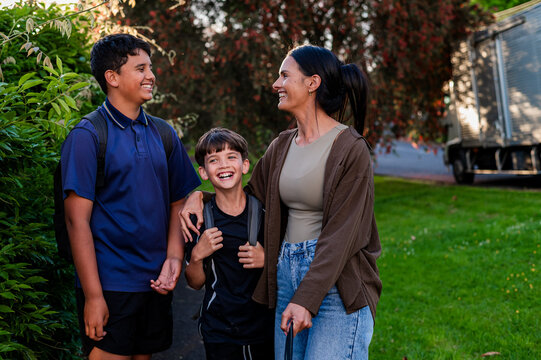 Maori mum welcoming two sons on paved pathway while holding a leash