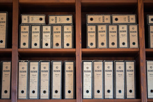 A collection of old cardboard document archive boxes neatly arranged on wooden shelves