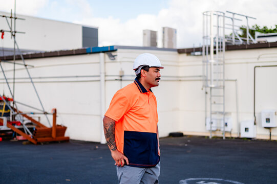 A construction worker in bright gear moves confidently across the work site under clear skies