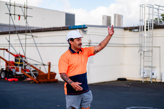Man in work clothes waving his hand at the worksite