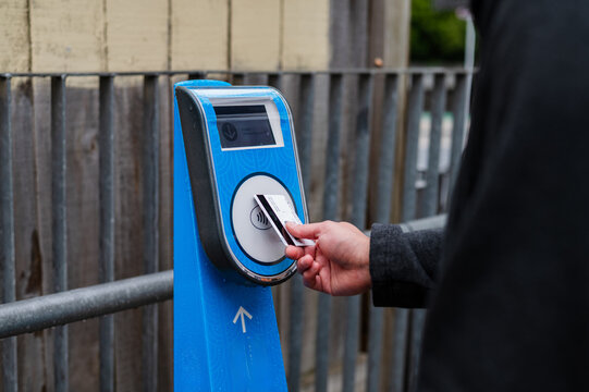 Close up of female hand tapping contactless card on ticket machine at the train station