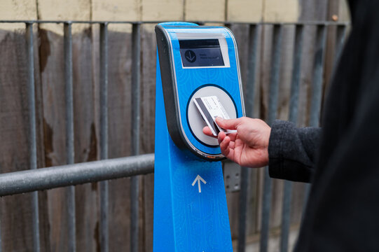 Close up of a female hand tapping contactless card on ticket machine at the train station