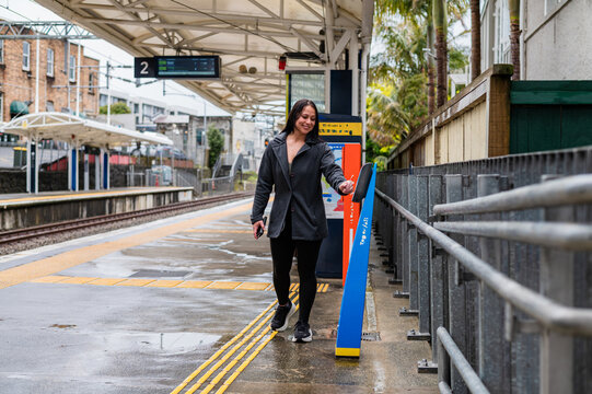 Mixed race woman tapping contactless card on ticket machine at the train station