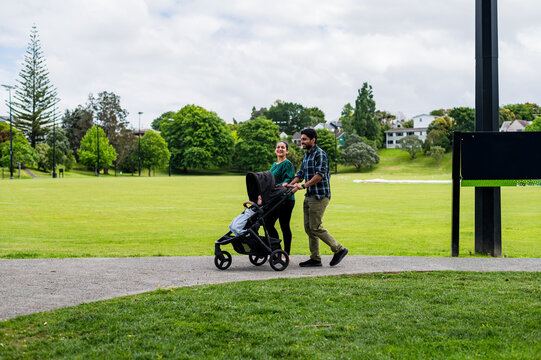 A couple pushing a pram with their child along a path in McLeod Park