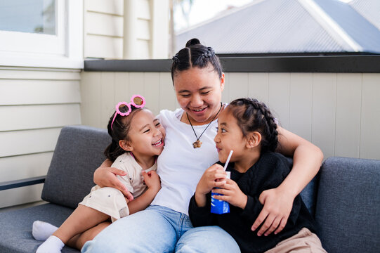 Teenage Samoan girl holding her younger siblings closely while seated on the couch