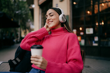 Cheerful young woman laughing while looking at tablet in modern environment, happy female user...