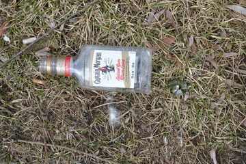 Naklejka premium top down view of a discarded plastic bottle (or mickey, pint, flask) of Captain Morgan spiced rum on burnt out grass in Toronto