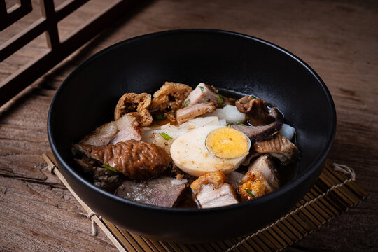 Traditional Thai rolled rice noodle soup (Kuay Jap) with crispy pork, boiled egg, and offal in a rich savory broth.
