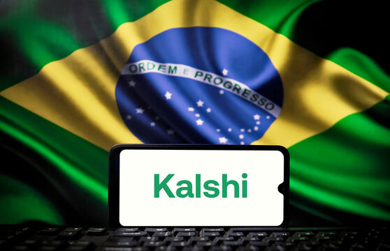 Kalshi logo on a smartphone screen with the Brazilian flag in the background. The American giant in the forecasting market, Kalshi, partners with the Brazilian company XP.