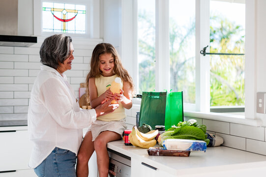 Grandmother checking the bottle label with a young girl sitting in a bright kitchen