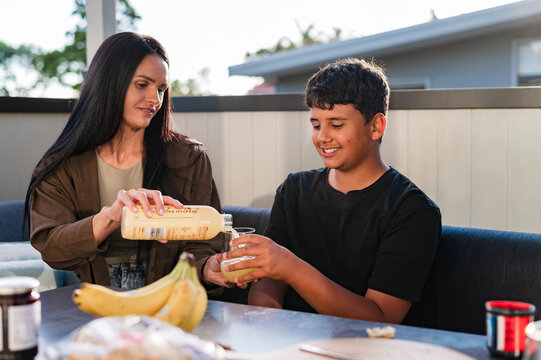 Maori mum pouring a drink into teenage sons glass