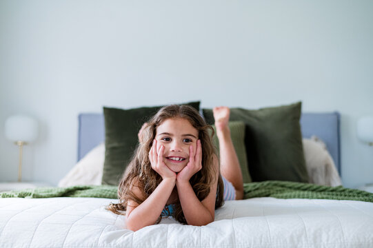 Young girl lying on her belly on the bed with her hands under her chin