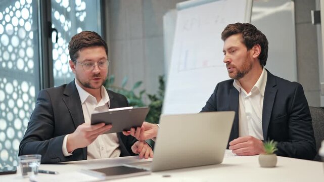 Professional men finalize business agreement in office. Signing documents leads to successful partnership. Expressing satisfaction, trust, and collaboration with a handshake. Achievement and teamwork.