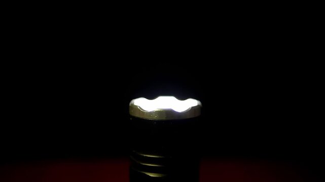 A black tactical flashlight stands upright emitting a rapid strobing light in total darkness. Concept of emergency signaling, distress SOS patterns, tactical operations, and security.