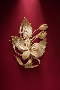 Decoration of straw on a red background. Branch with flowers. Boutonniere made out of straw. Brooch. Straw weaving.