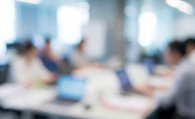 Fototapeta premium A blurry image of a modern office workspace with people engaged in discussions and using laptops, depicting a collaborative work environment.