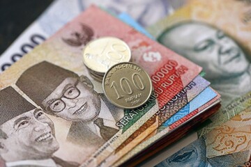Indonesian rupiah money bills and sen coins pile on table. Indonesia coins on banknotes of IDR currency close up. Concept of business, taxes and banking in Indonesia © mehaniq41