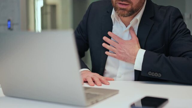 Professional feels intense chest pain, gripping chest, struggling with discomfort. Worry, anxiety evident. Health crisis or stress-related symptoms manifest at workstation. Medical emergency possible.