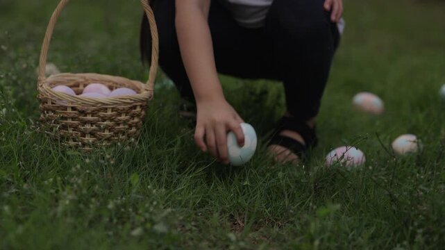 slow motion of child girl walking and hunting for Easter eggs into a basket on green grass in the garden