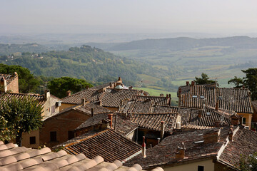 Obraz premium Traditional terracotta rooftops of the medieval hilltop town of Montepulciano in Tuscany, Italy, overlooking the soft rolling countryside of the Province of Siena during autumn. 