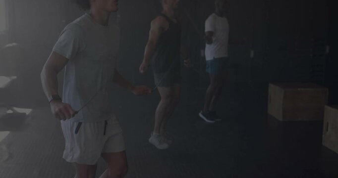 Vertical video: Left jumper starting skipping, three men syncing rhythm, skipping ropes in gym
