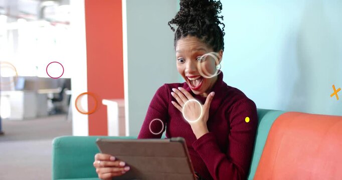 Woman holding tablet glancing at screen sparking tech shapes around her smiling at content on couch
