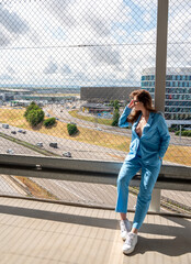 Fototapeta premium Elegant woman wearing a blue suit relaxing in the summer sunlight