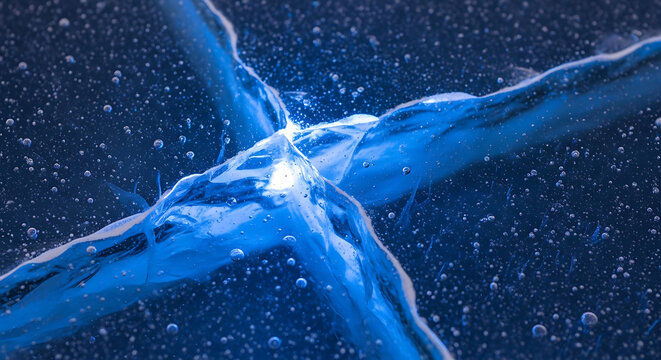 Deep blue frozen ice surface with complex crack patterns and trapped oxygen bubbles in the winter