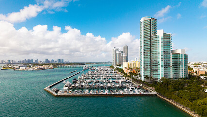 Fototapeta premium Marina Bay filled with vessels and yacht in Miami. Summer vacation scene with yachts by the oceanfront. Skyline with yachts in Miami. Florida coastline from above with boats. Boat trip in the Miami.