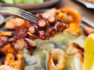 grilled octopus tentacle on fork with seafood pieces and lemon closeup dish with sauce delicious restaurant meal © Татьяна Швец