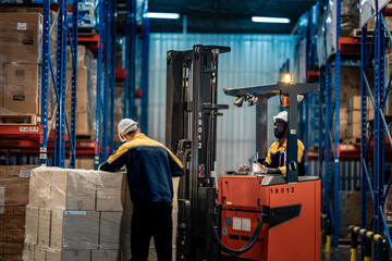 Naklejka premium Rear view of logistics manager checking commercial package pallet while forklift operator giving thumbs up. Safe transport and inventory distribution in modern factory storehouse.